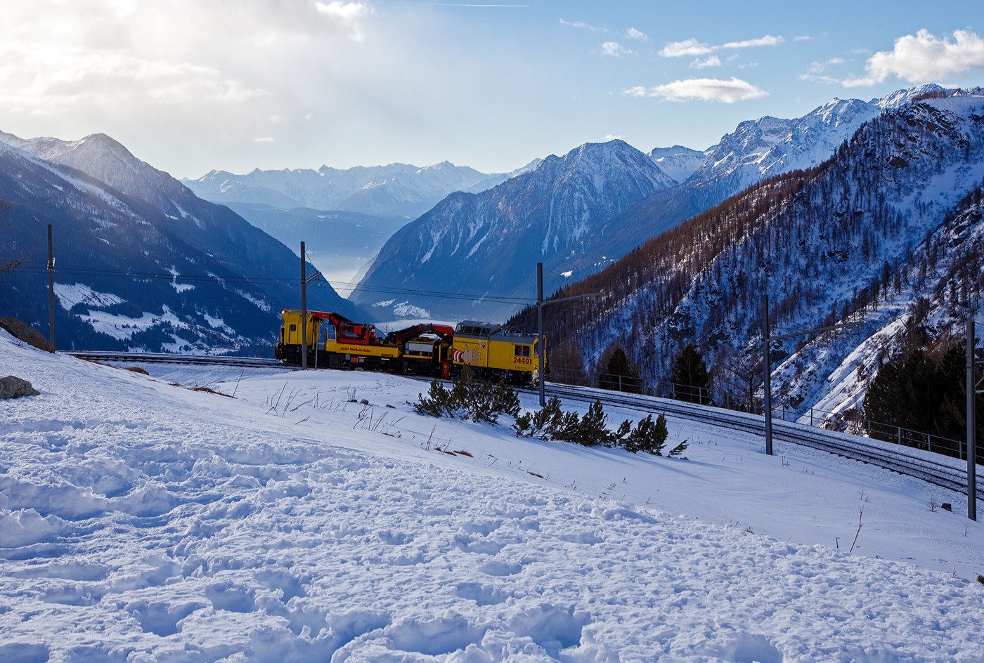 Der RhB (Rhätische Bahn) Xmf 6/6 24401, ex 92020, ein Fahrleitungsturmwagen vom Typ Plasser & Theurer MTW 100.160 fährt am 20 Februar 2017 vom Bahnhof Alp Grüm (2.091 m ü. M.) durch die Himmelskurve hinab ins Puschlav bzw. in Richtung Tirano.